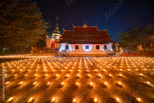 candles ligt around it in a temple. Candles burning around in area of front of chapel or church. Light of Lanna Candle Trays in loy krathong night. Yi peng festival Chiang Mai Thailand.. © somchairakin