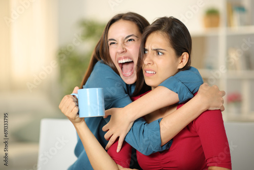 Excited woman hugging to an upset friend photo