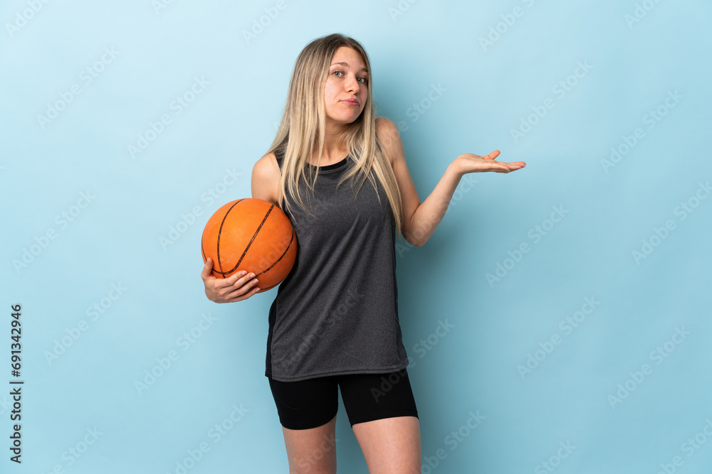 Young blonde woman playing basketball isolated on blue background having doubts with confuse face expression