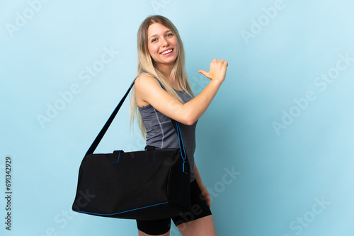 Young sport woman with sport bag isolated on blue background proud and self-satisfied