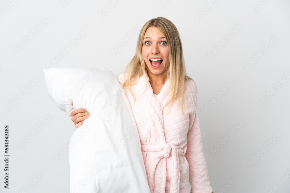 Young blonde woman isolated on white background in pajamas and with surprise and shocked facial expression Young blonde woman isolated on white background in pajamas and with surprise and shocked facial expression