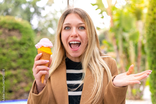 Young pretty blonde woman with a cornet ice cream at outdoors with shocked facial expression