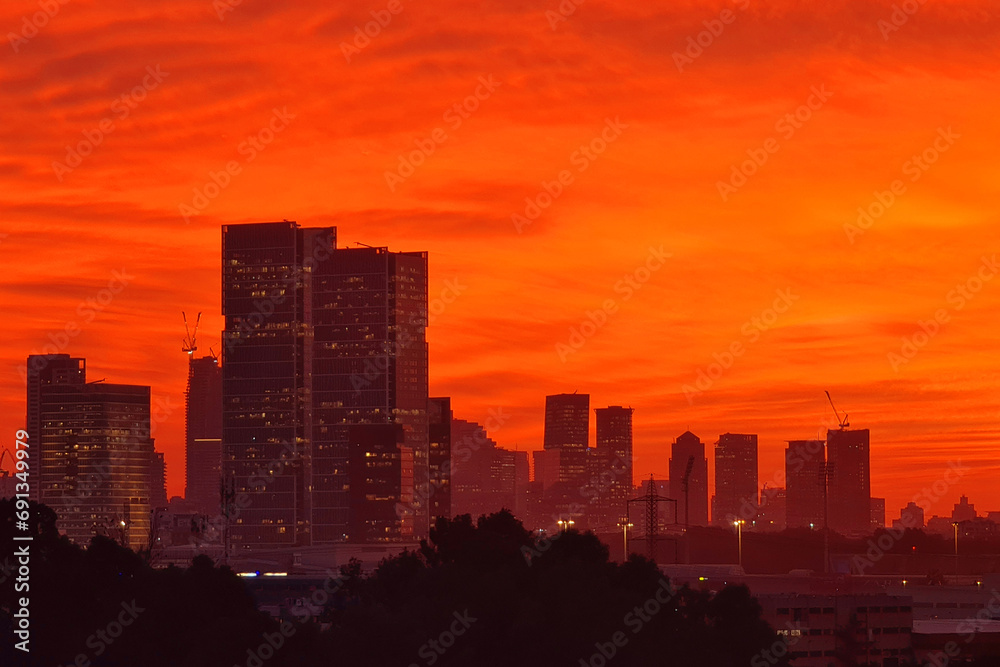 Skyline of city at sunset. Cityscape abstract red background. Red sky with clouds over the city, panoramic view. Sunset over Tel Aviv, Israel