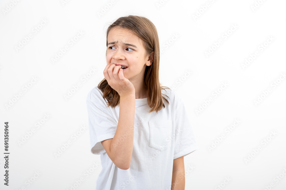 Scared and anxious girl, biting her fingernails on a white background isolated. Scared and anxious girl, biting her fingernails on a white background isolated.