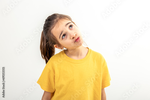 Funny little girl looks up shyly on a white background isolated. photo