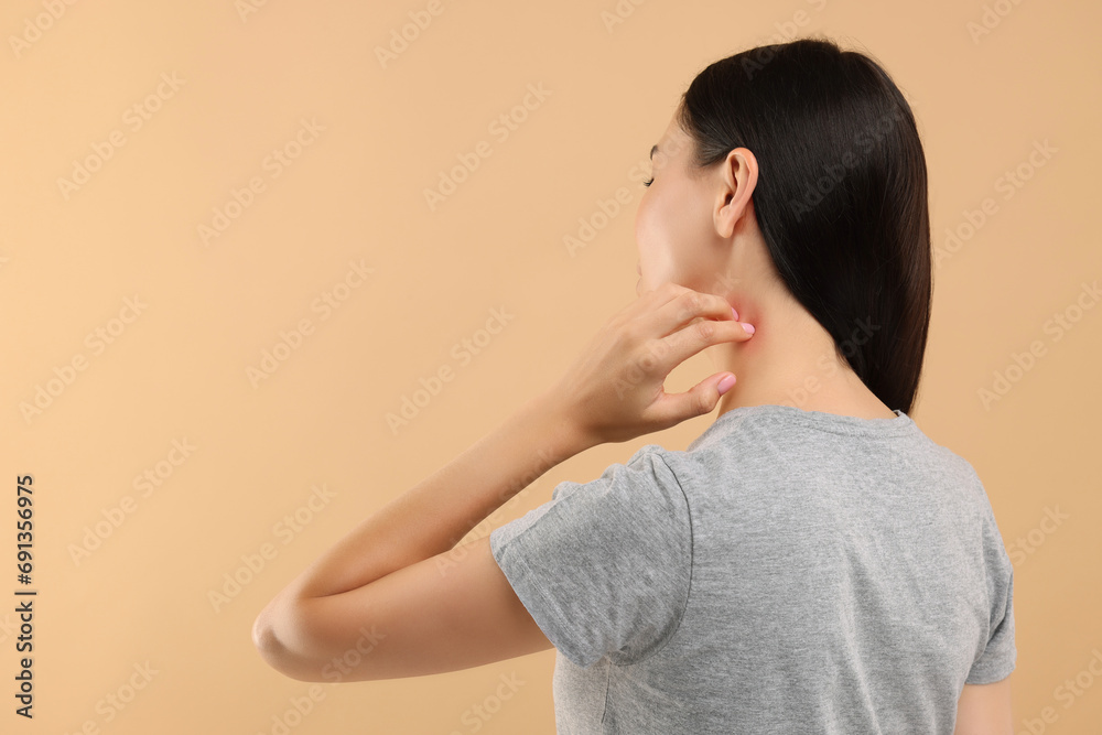 Suffering from allergy. Young woman scratching her neck on beige background, back view. Space for text Suffering from allergy. Young woman scratching her neck on beige background, back view. Space for text