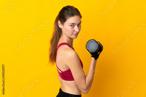 Young Ireland woman isolated on yellow background making weightlifting