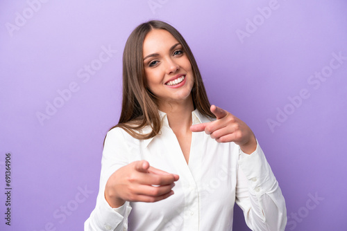Young caucasian woman isolated on purple background pointing front with happy expression