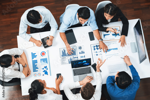 Top view analyst team utilizing BI Fintech to analyze financial data at table in meeting room. Analytic BI dashboard power on paper for business insight and strategic marketing planning. Prudent