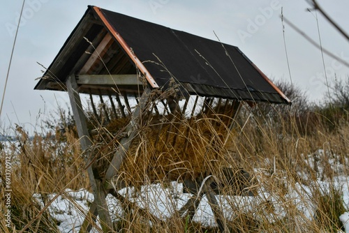 A snowy hay rack in winter. Feeding rack filled with hay and ready for winter feeding of game animals. Concept of the end of the hunting season and preparation for winter feeding of deer