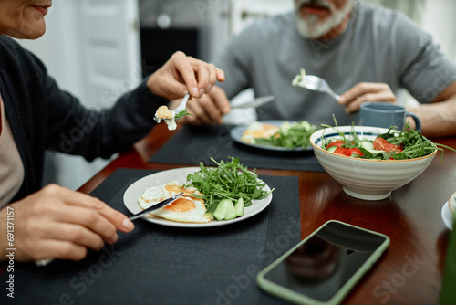 Couple eating fried eggs and salad for breakfast at home photo