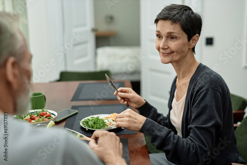 Adult woman looking at her husband while eating fried eggs and salad photo