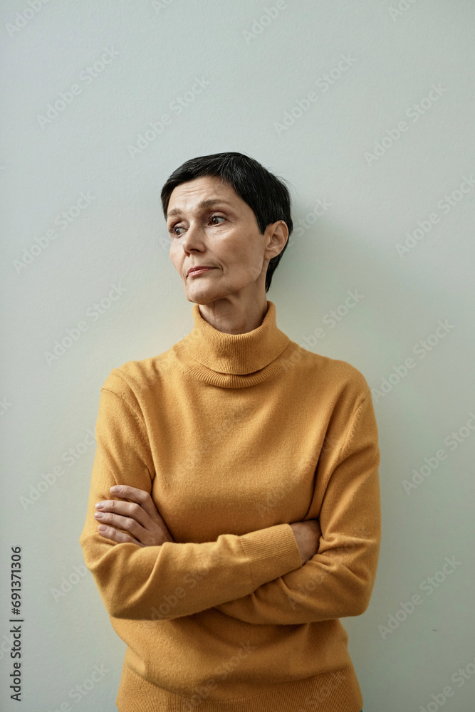 Pensive woman in yellow turtle-neck crossing hands on chest Pensive woman in yellow turtle-neck crossing hands on chest