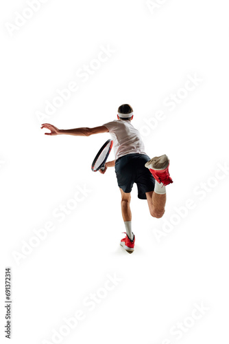 Back view image of young man in motion with racket, tennis player during game, training isolated over white background. Concept of sport, hobby, active and healthy lifestyle, competition