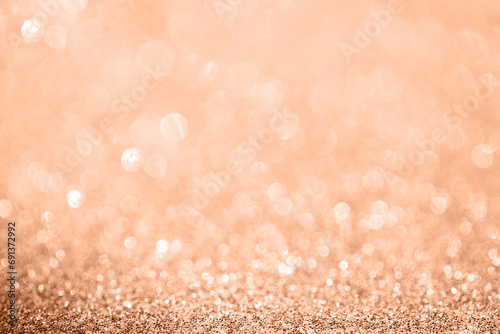 Diamond coral bokeh texture with sparkling particles festive background in color of the year 2024 Peach Fuzz