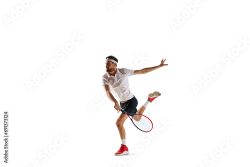 Concentered young man, tennis payer in motion during game, training, hitting ball with racket isolated over white background. Concept of sport, hobby, active and healthy lifestyle, competition © master1305