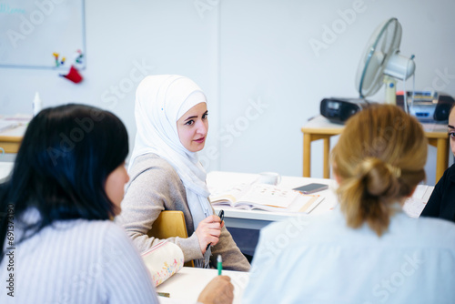 Woman wearing hijab talking to multi-ethnic friends in classroom photo