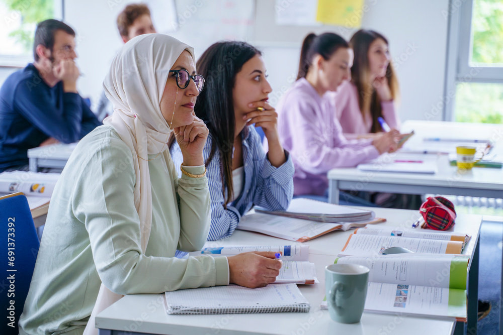 Multi-ethnic students at desk studying together in classroom Multi-ethnic students at desk studying together in classroom