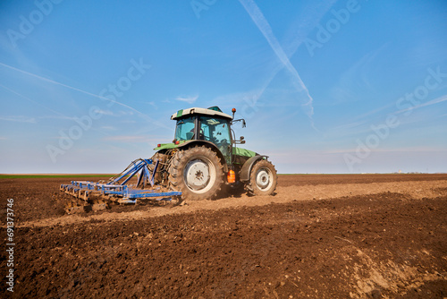 Tractor plowing field in early spring photo