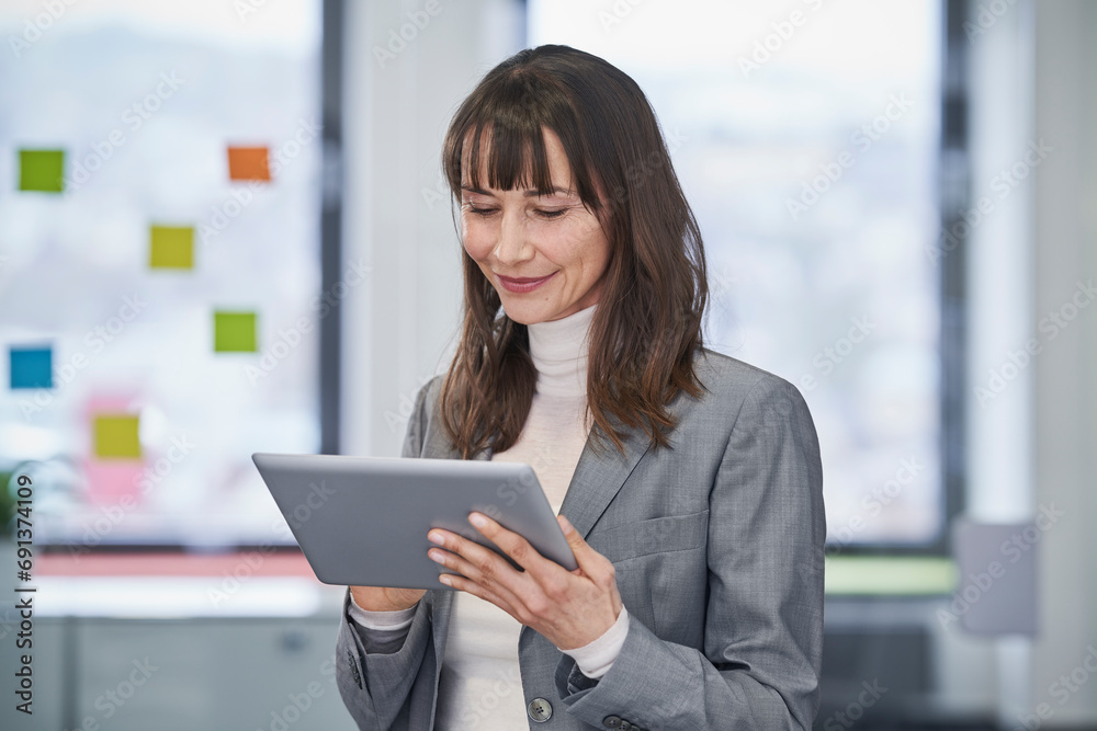 Smiling mature businesswoman using tablet PC in office Smiling mature businesswoman using tablet PC in office