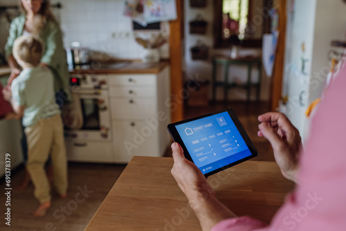 Man using smart thermostat, adjusting, lowering heating temperature at home. Concept of sustainable, efficient, and smart technology in home heating and thermostats.