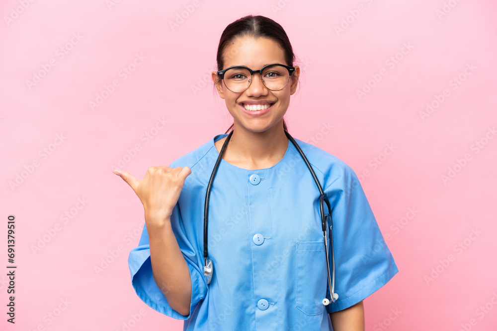 Young nurse Colombian woman isolated on pink background pointing to the side to present a product Young nurse Colombian woman isolated on pink background pointing to the side to present a product