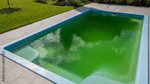 Green water in a home pool in the backyard of a house. Bloomed due to incorrect dosage of chemicals