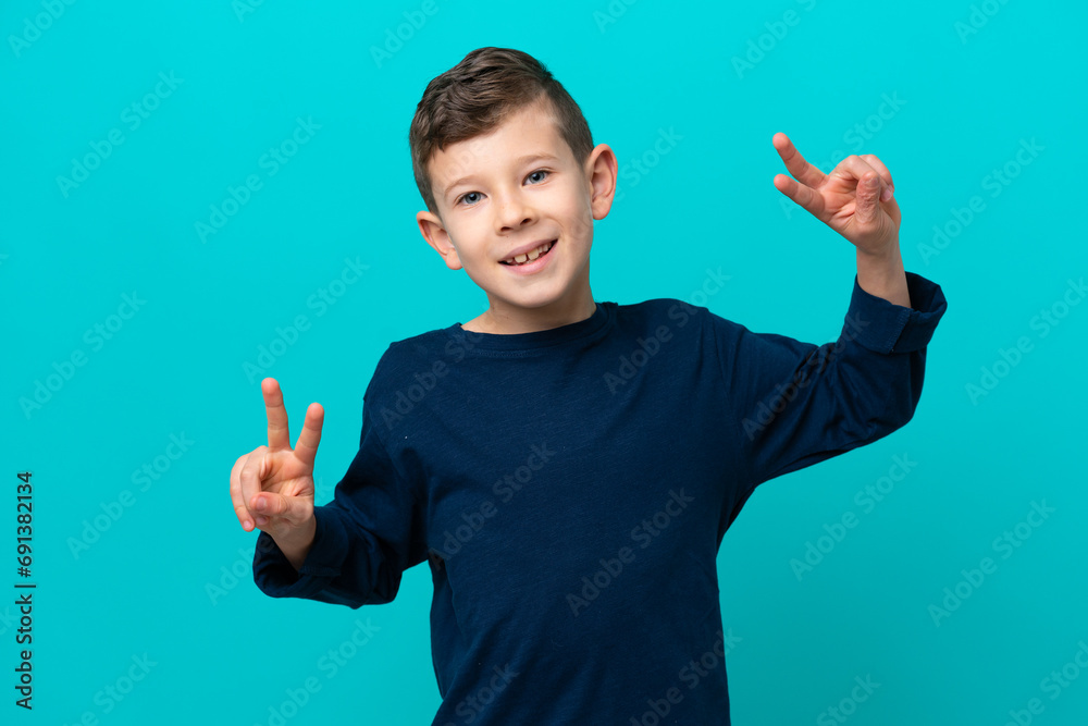 Little kid boy isolated on blue background showing victory sign with both hands Little kid boy isolated on blue background showing victory sign with both hands