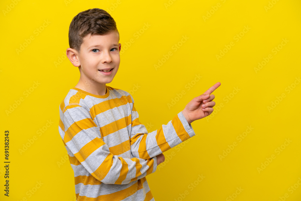Little caucasian boy isolated on yellow background pointing finger to the side Little caucasian boy isolated on yellow background pointing finger to the side