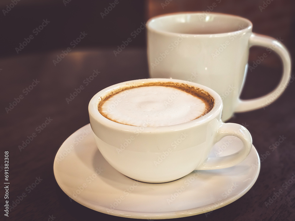 Hot cappuccino coffee in a mug Placed on the table in a warm atmosphere. Hot cappuccino coffee in a mug Placed on the table in a warm atmosphere.