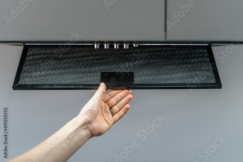 Fotografie Woman hand taking aluminum mesh filter from extractor hood
