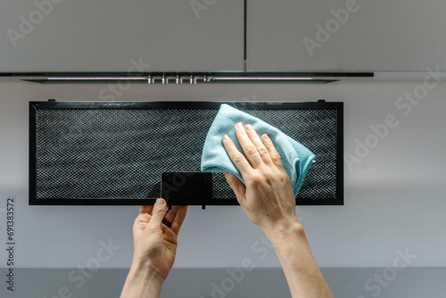 Close up of woman hands holding filter from extractor hood and removing dirty with cloth photo