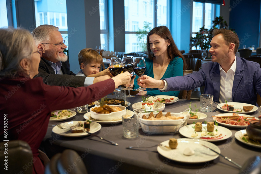 Happy family clinking glasses at a table while celebrating Christmas