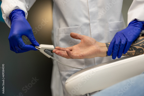 Nurse measuring pressure and oxygen level in male finger.