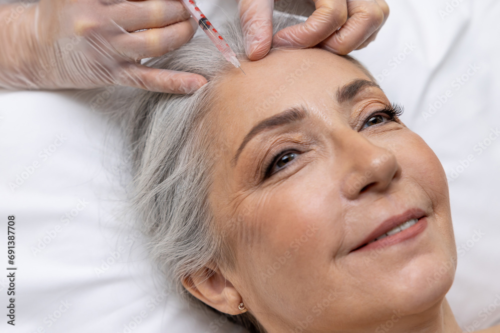 Naklejka premium Beautician making beauty injections into forehead area