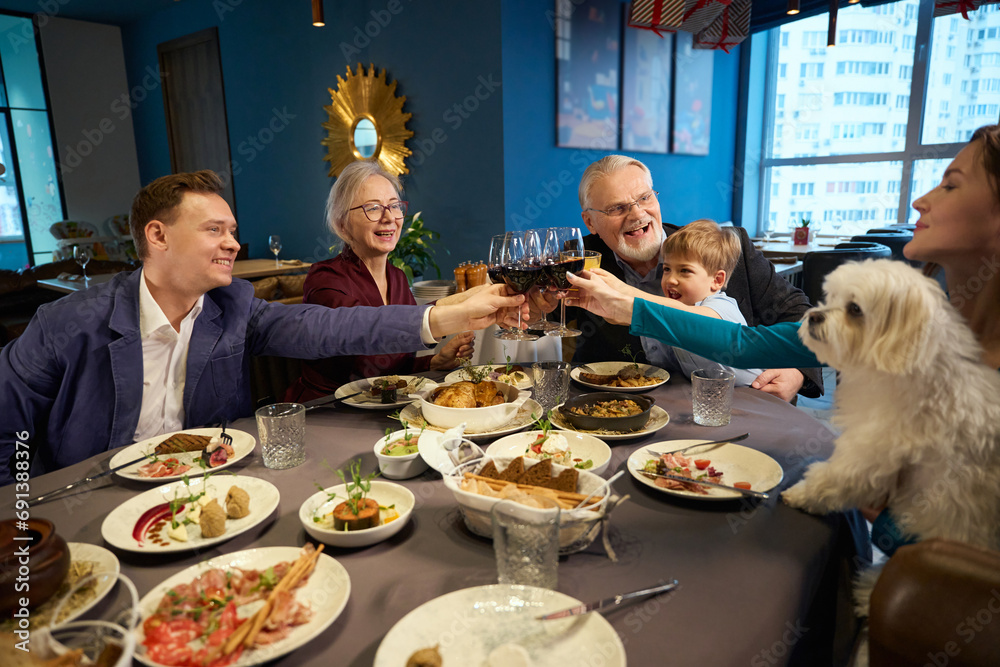 Cheerful women men little boy celebrating New Year with wine in restaurant Cheerful women men little boy celebrating New Year with wine in restaurant