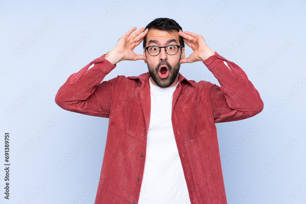 Young caucasian man wearing corduroy jacket over blue background with surprise expression Young caucasian man wearing corduroy jacket over blue background with surprise expression
