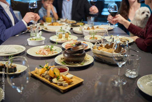 Delicious dishes on festive restaurant table unrecognizable people on background