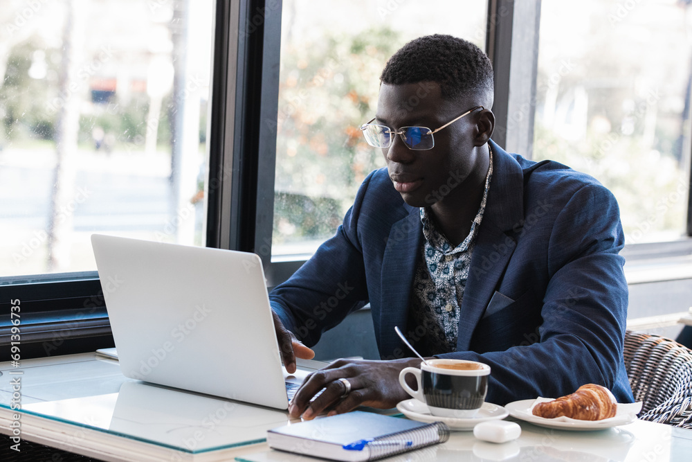 Portrait of black man working on laptop computer in busy cafe