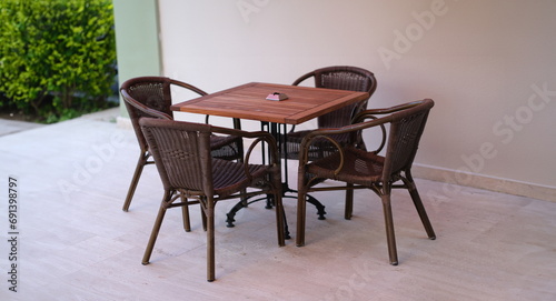 Wooden table with chairs standing on summer terrace. Outdoor furniture concept