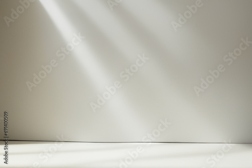 Minimalistic abstract light pearl color background for product presentation. Incident light from the window on the wall and floor.