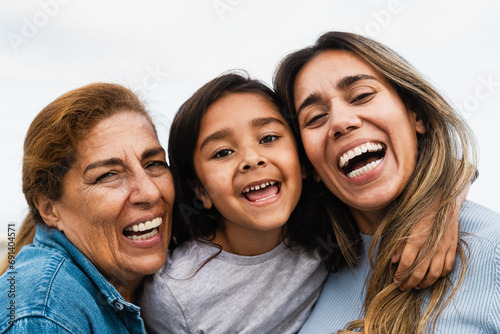 Happy Hispanic multigenerational family smiling into the camera - Child having fun with her mother and grandmother outdoor photo