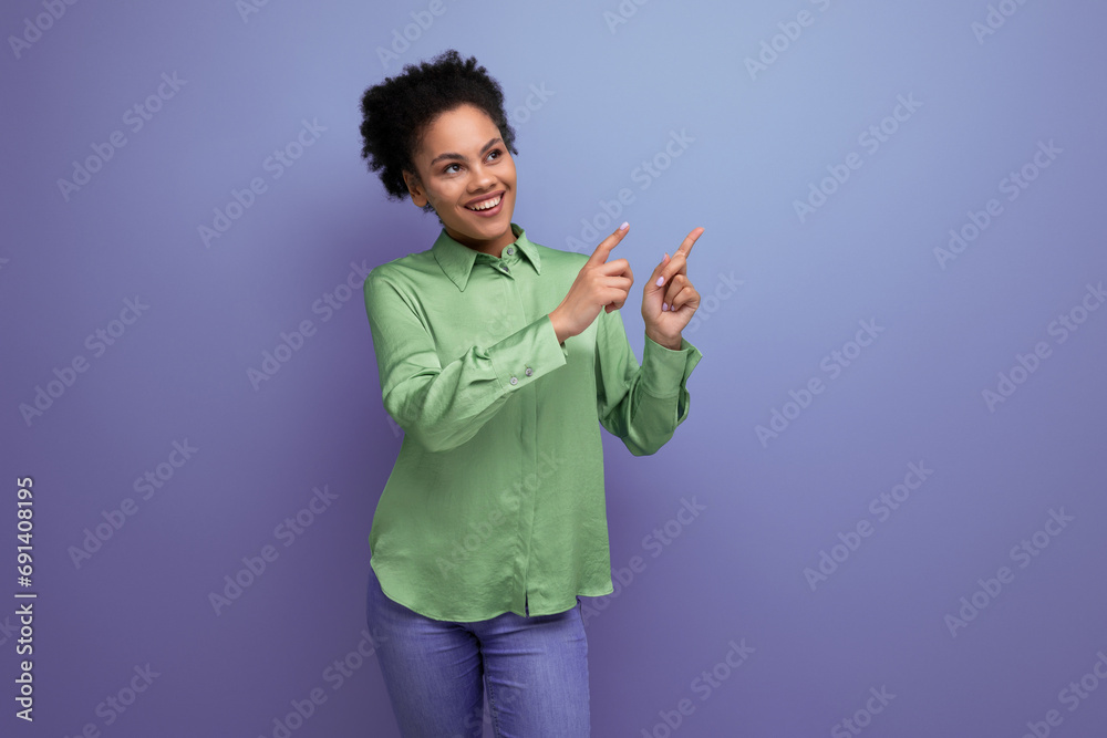 young female model with curly black hair dressed in a green blouse points with her hand at an advertisement on an isolated background with copy space young female model with curly black hair dressed in a green blouse points with her hand at an advertisement on an isolated background with copy space