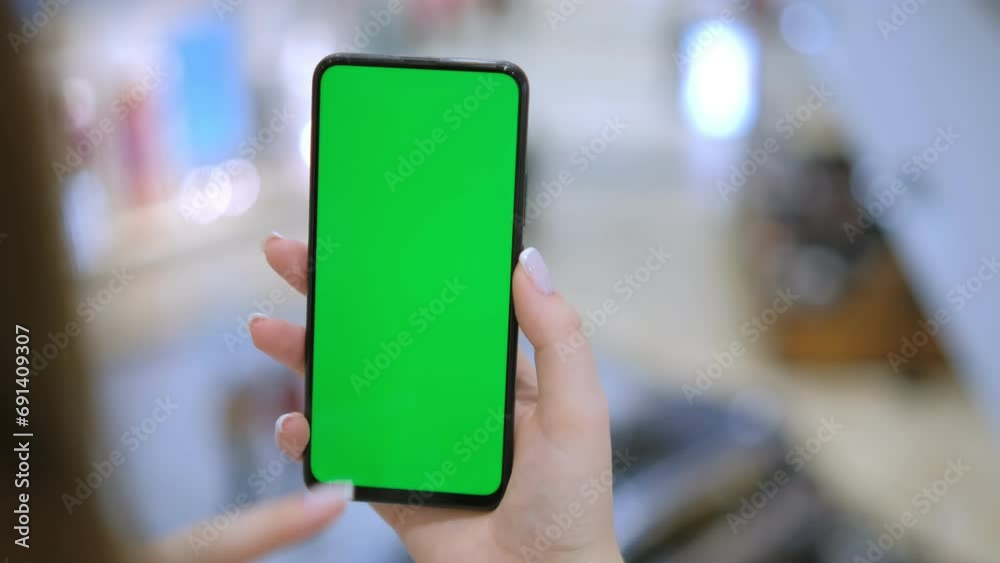 Back view of brunette holding chroma key green screen smartphone watching content. Shopping online. Shopping center 4K Back view of brunette holding chroma key green screen smartphone watching content. Shopping online. Shopping center 4K