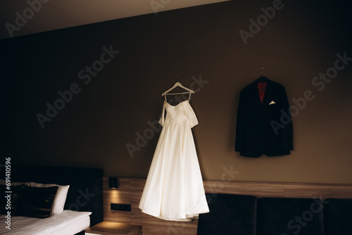 Bride and groom dresses hangs on the wall in the hotel photo