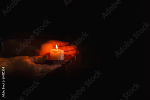 Religion concept.Concentration time.Remembrance of the dead.burning candle in a mans hand on dark background.Copy space.