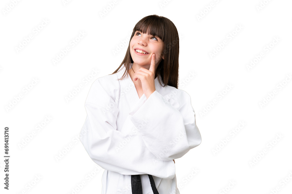 Little Caucasian girl doing karate over isolated background thinking an idea while looking up Little Caucasian girl doing karate over isolated background thinking an idea while looking up