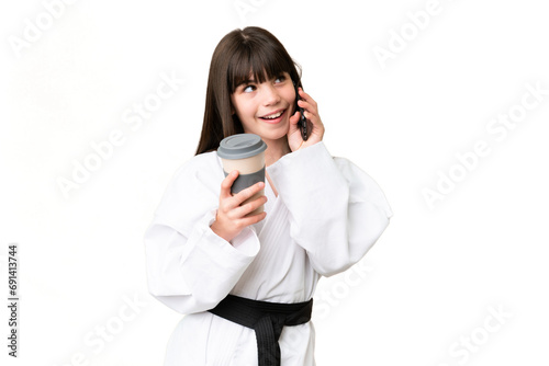Little Caucasian girl doing karate over isolated background holding coffee to take away and a mobile