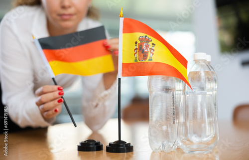 ..Young woman in business clothes puts flags of Germany and Spain on negotiating table in office