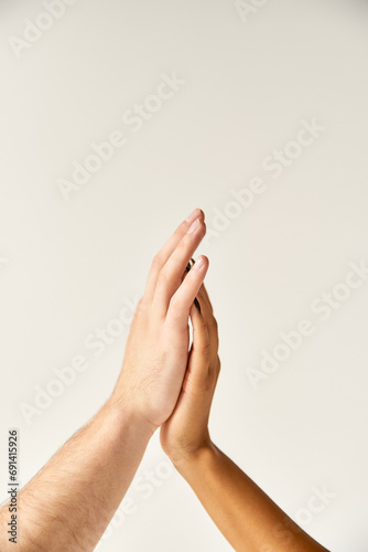 cropped view of interracial sexy couple touching hands and fingers of each other on ecru background